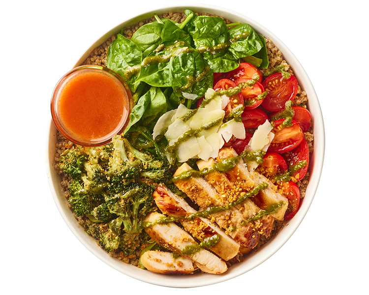 Freshii Chicken Pesto Parmesan bowl with grilled chicken, quinoa, spinach, grape tomatoes, broccoli, parmesan and pesto vinaigrette, served with hot sauce